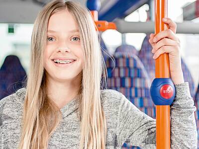 grinsendes Mädchen hält sich an einer Stange im Bus fest