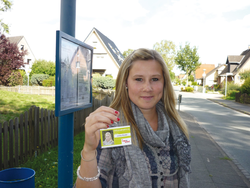 Frau zeigt Fahrerbegleitungskarte an einer Bushaltestelle
